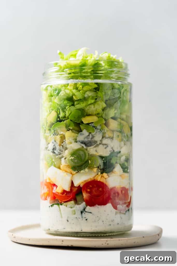 Adding lettuce to a jar to make a salad in a jar.