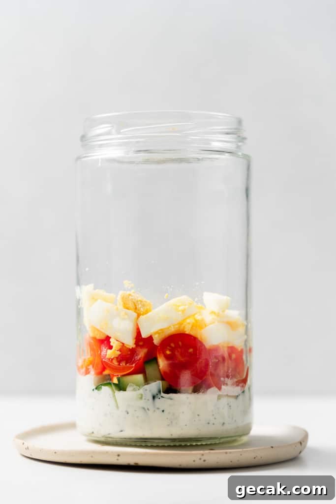 Adding vegetables and hard-boiled eggs to a mason jar.