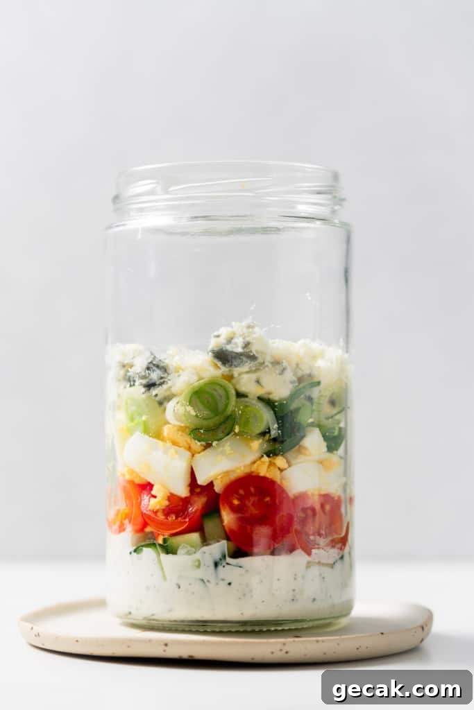 Layering salad ingredients in a glass jar.