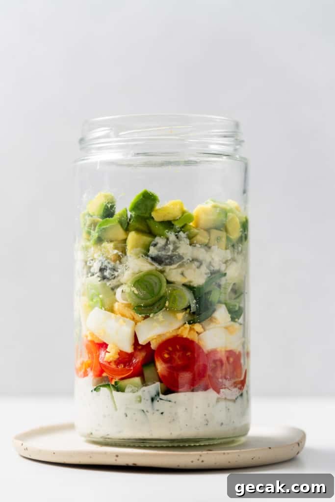Filling a glass jar with tomatoes, cheese and avocado.