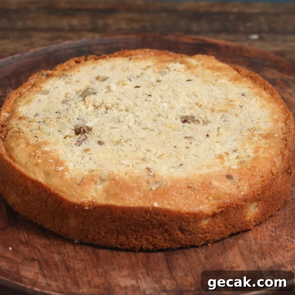 Baked Italian Cream Cake layer with pecans and coconut on a wooden plate