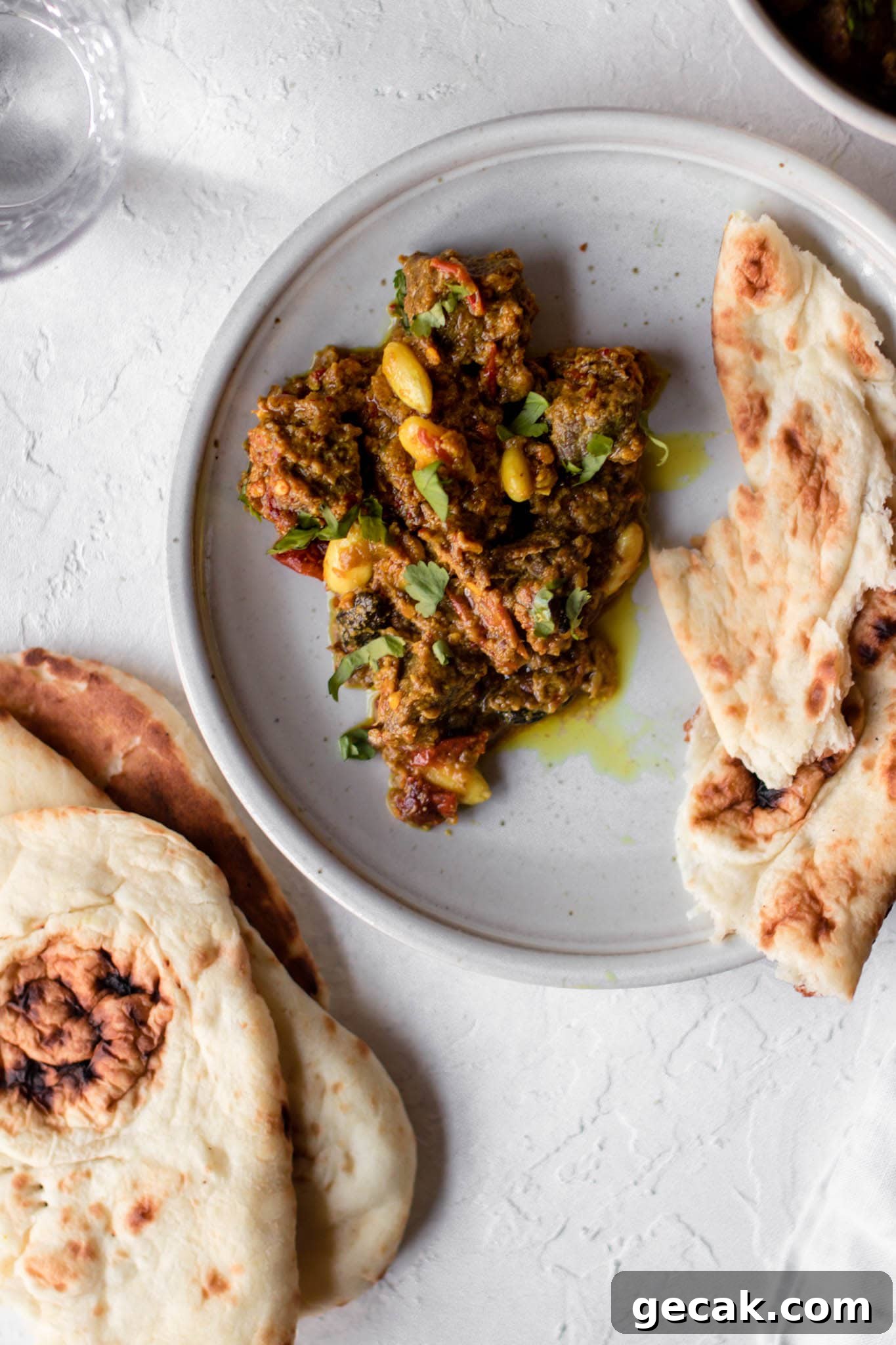 Close up of Pakistani style Beef Curry (Stew) on a plate with naan on the side