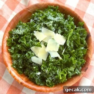 Massaged kale salad topped with shaved Parmesan and lemon dressing in a brown bowl on a orange checkered background.