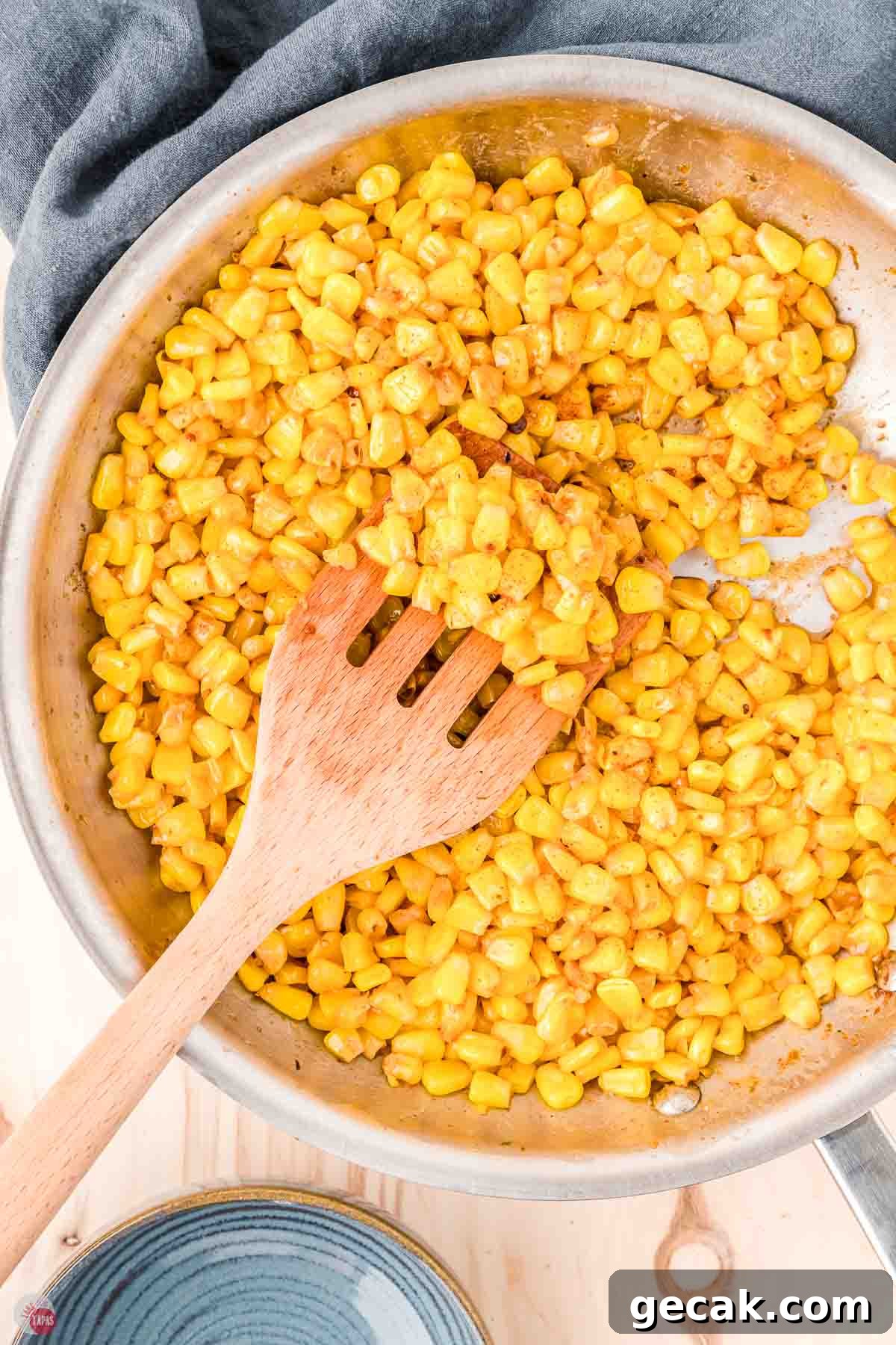fried corn in a skillet and a wood spoon