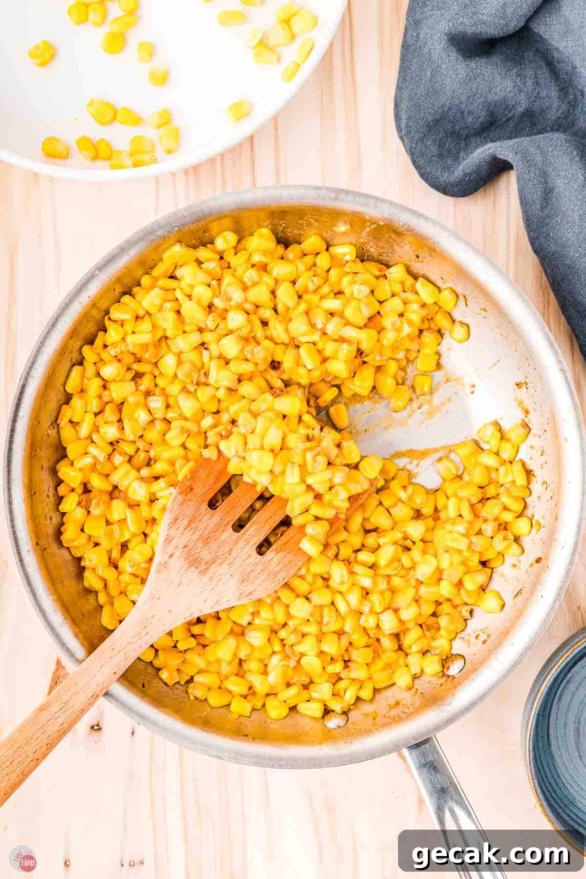 wood spatula moving corn around a skillet