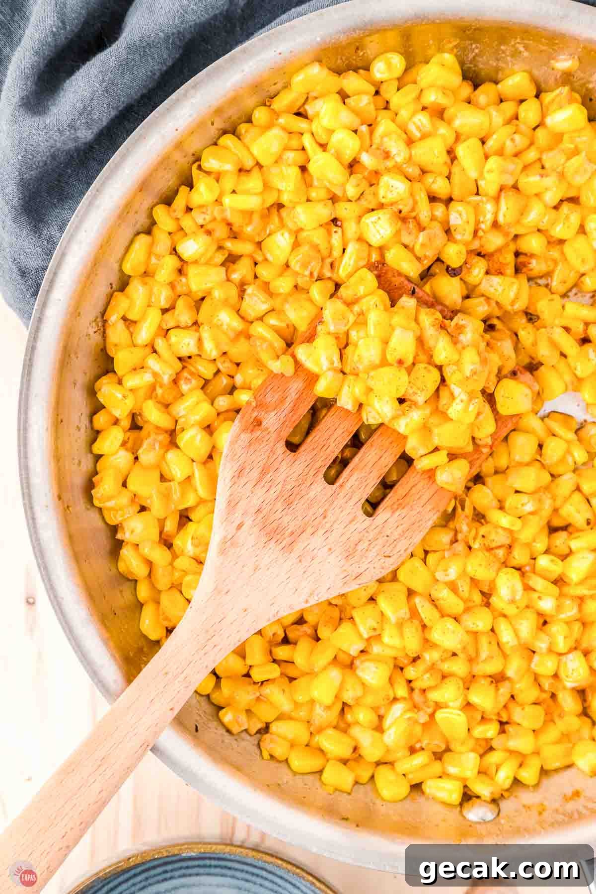 skillet of yellow corn with a wood spoon