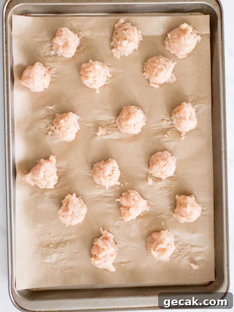 chicken meatballs on a parchment lined sheet pan
