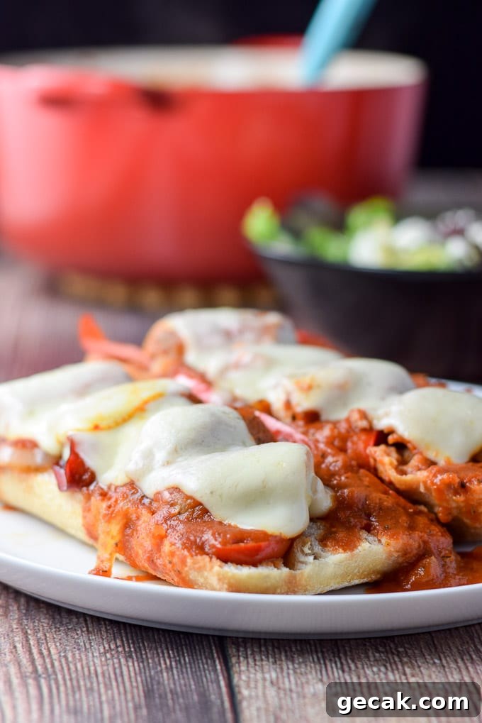 A near vertical view of a white plate with the bread covered with sausage, veggies, gravy and melted cheese