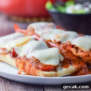 A vertical view of a white plate with the bread covered with sausage, veggies, gravy and melted cheese - square