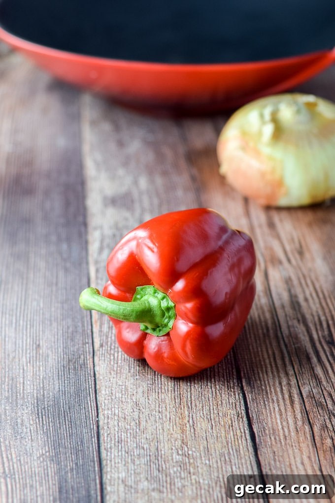 Red bell pepper and onion with a red wok in the background