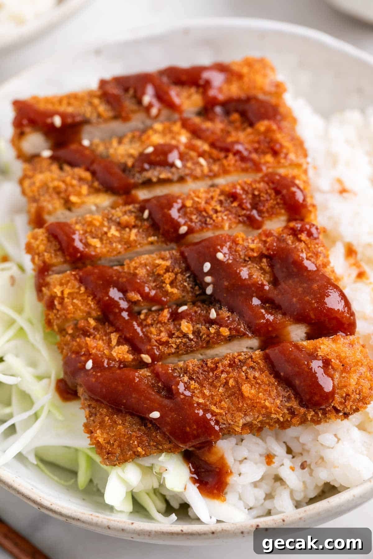 Tofu katsu with rice, shredded cabbage, and sesame seeds in a bowl.