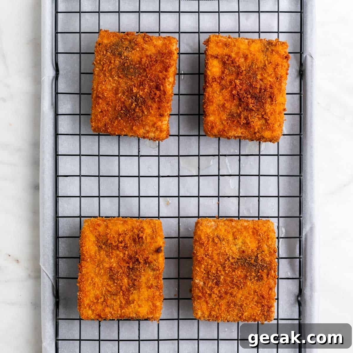 Cooked tofu pieces on a wire rack on a lined baking sheet.