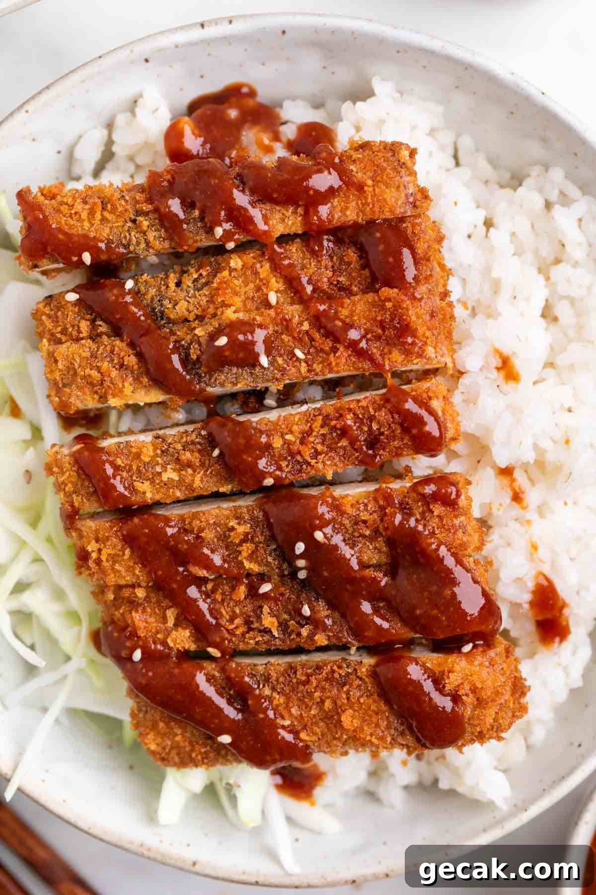 Bowl filled with rice, tofu katsu, cabbage, and sesame seed topping.