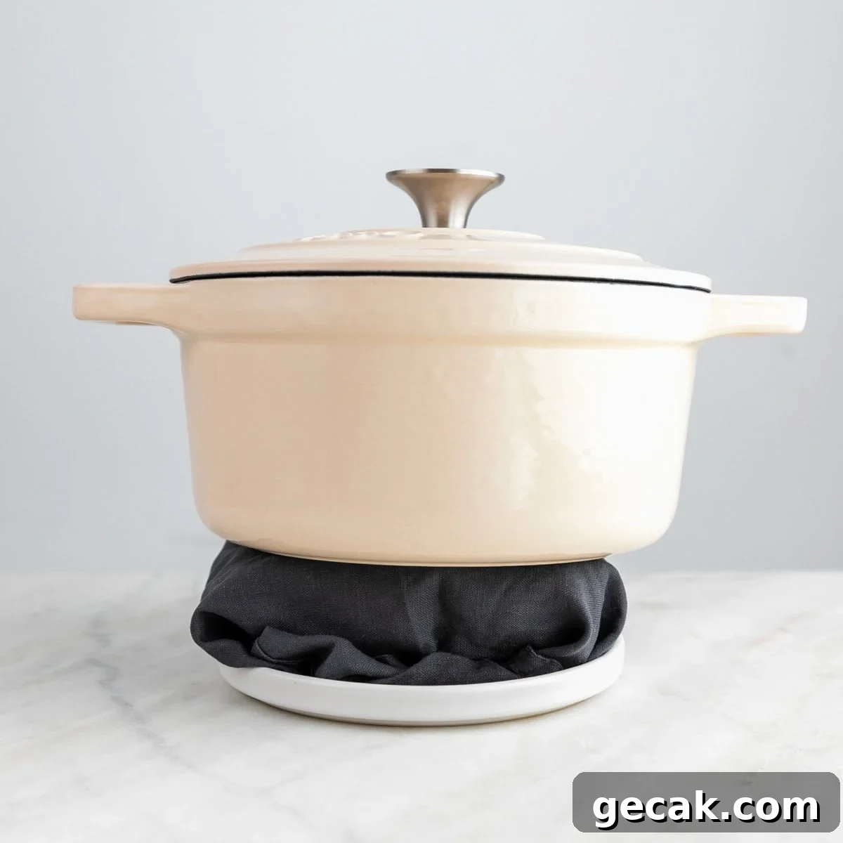 Tofu wrapped in a clean towel on a plate with a pot on top.