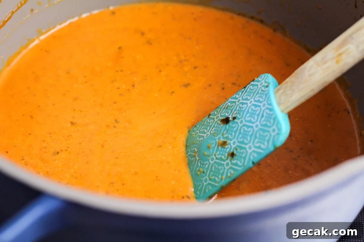 Tomato basil soup being stirred in pot.