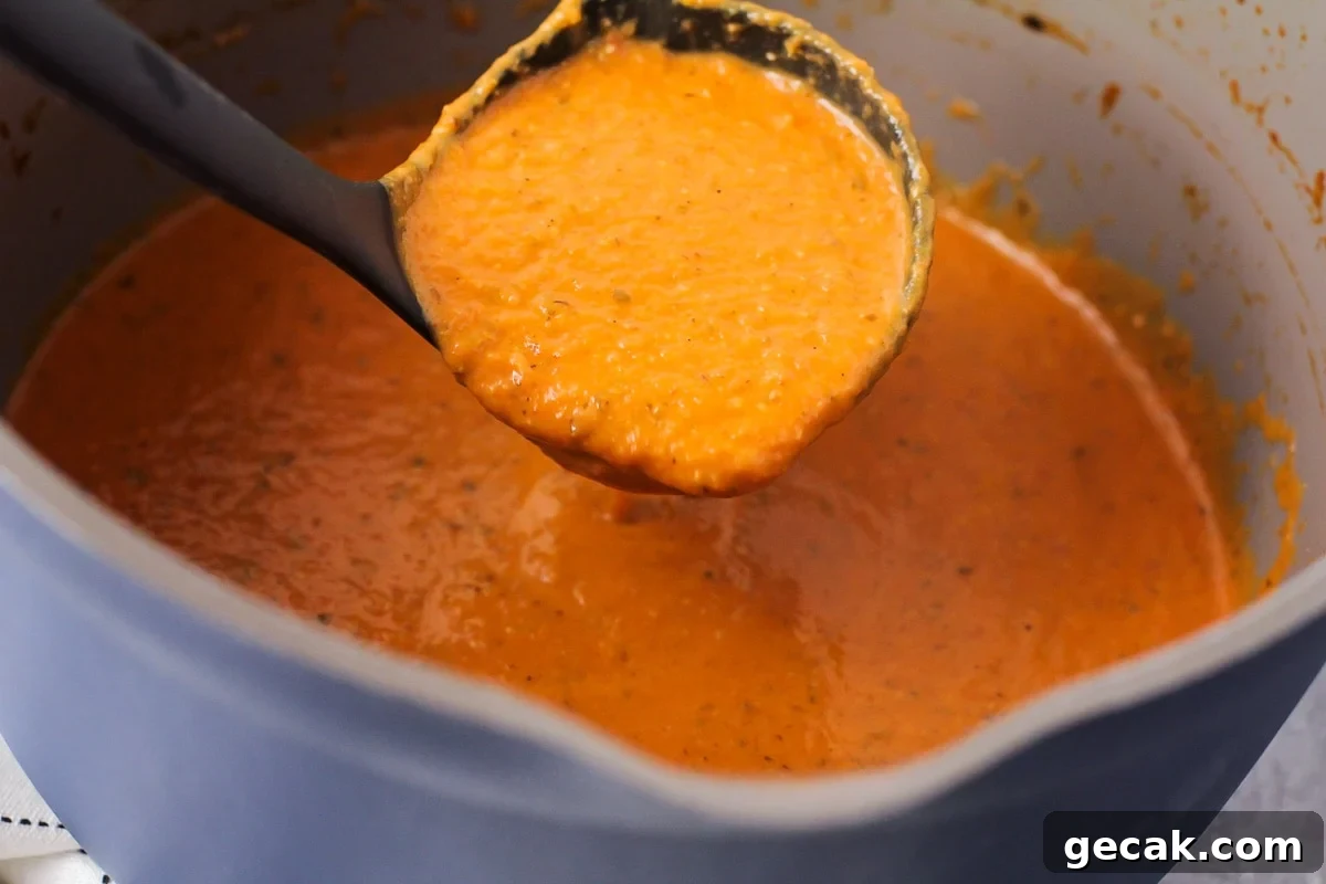 Tomato basil soup being ladled out of pot.
