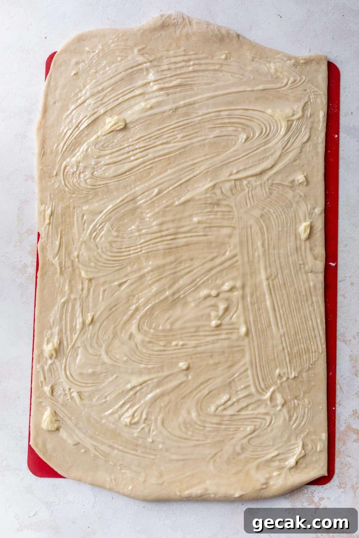 overhead view of a rectangle of vegan cinnamon roll dough slathered with butter.