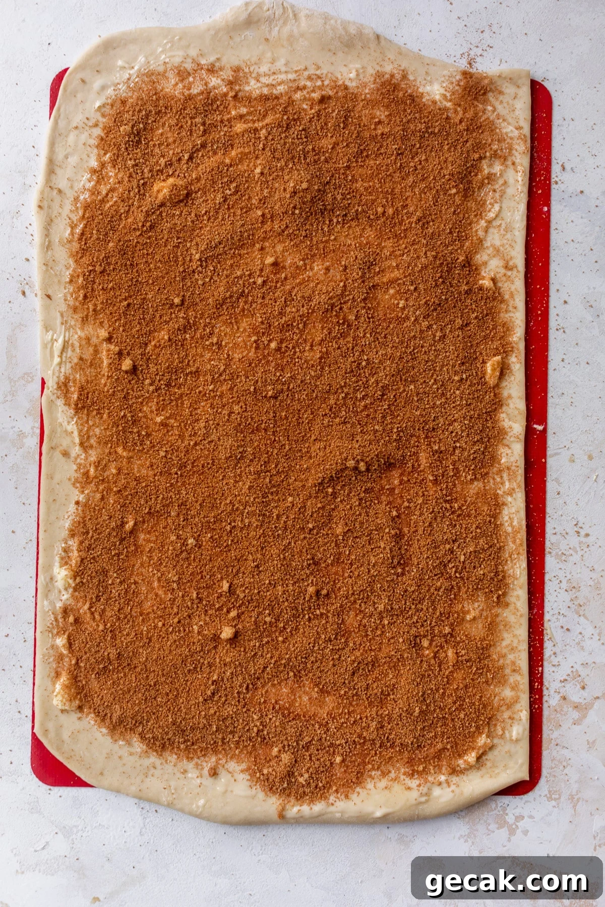 overhead view of a rectangle of vegan cinnamon roll dough topped with a layer of cinnamon sugar.