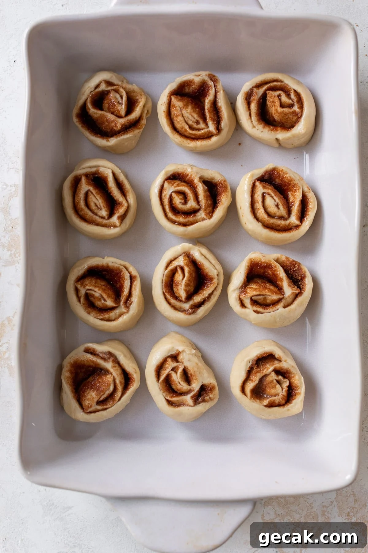 overhead view of unbaked vegan cinnamon rolls in a white baking dish.
