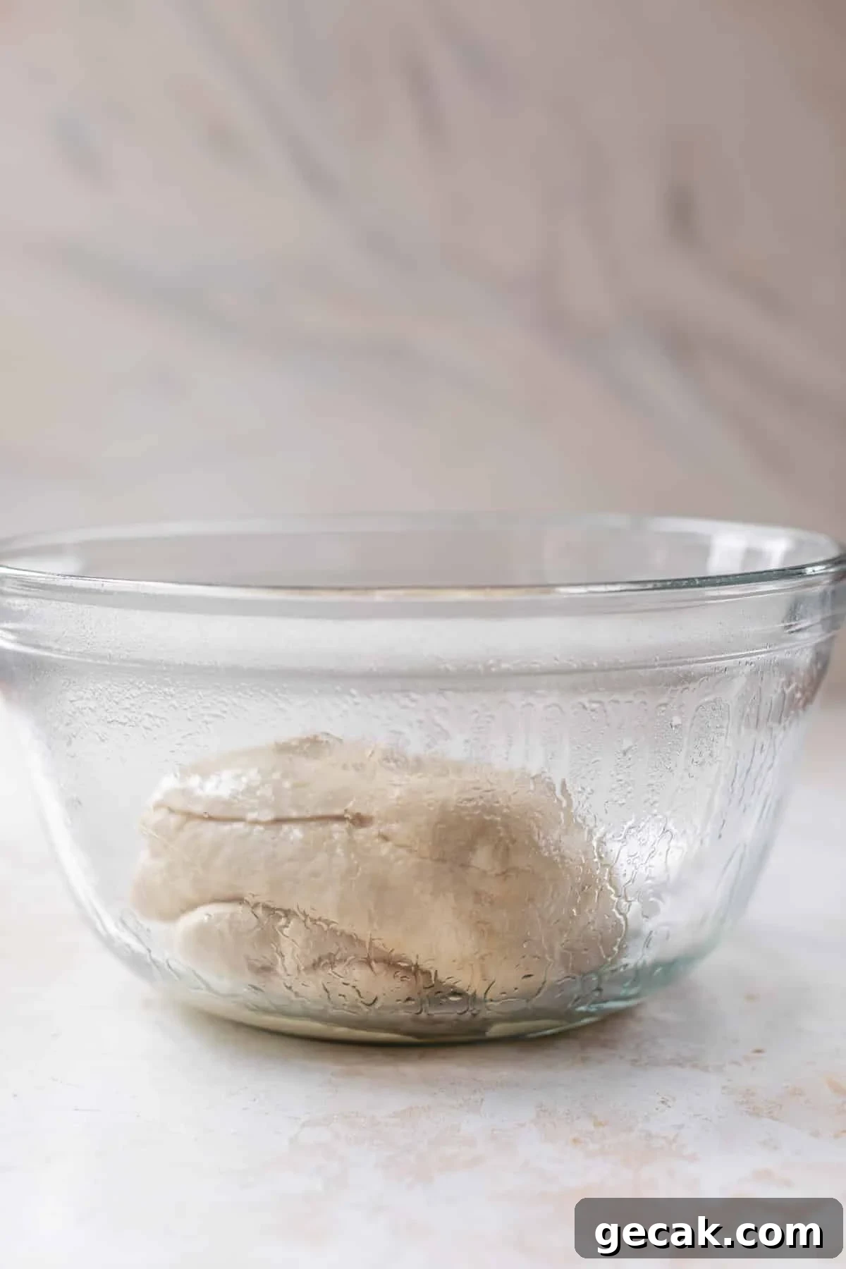 side view of vegan cinnamon roll dough in a glass bowl.