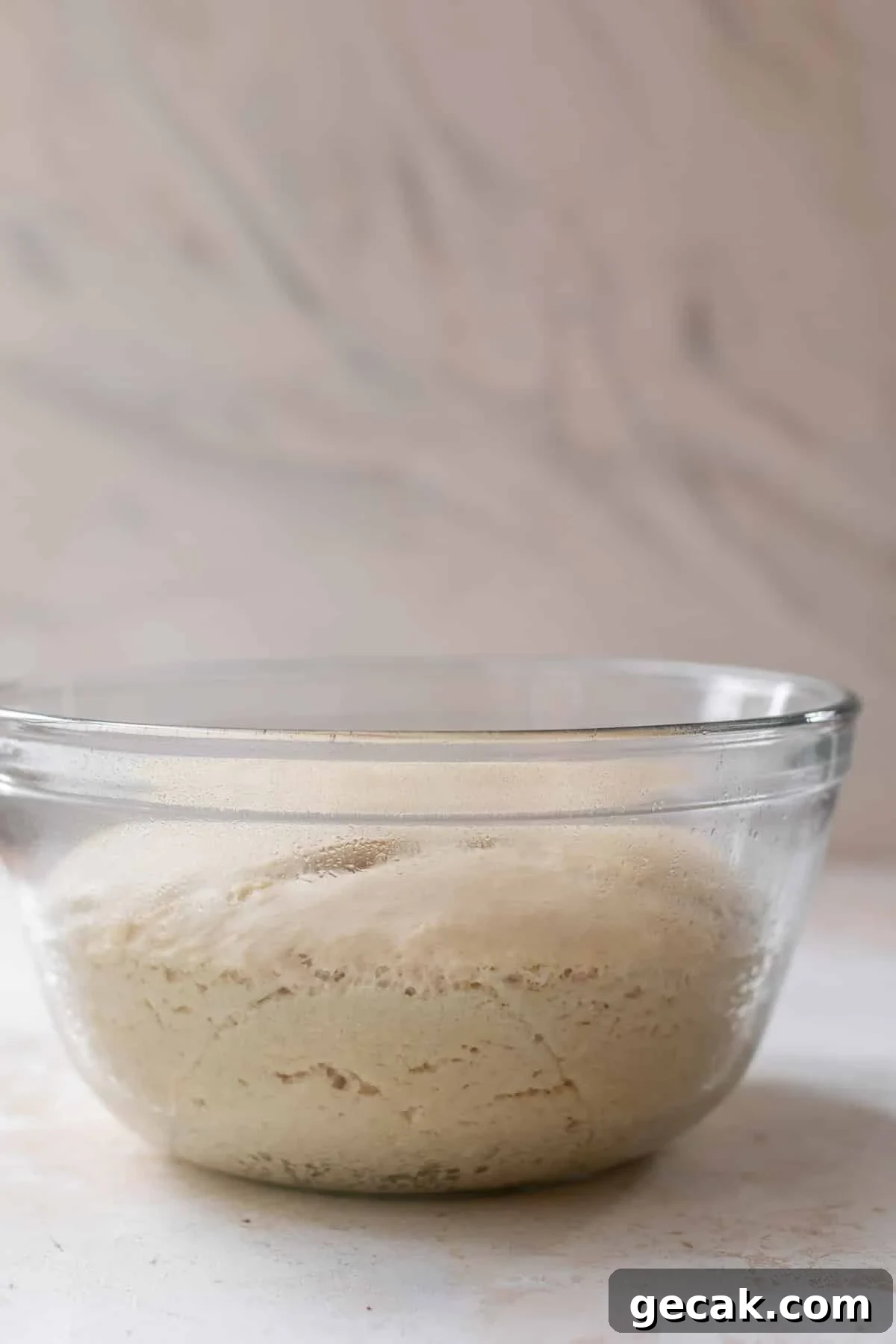 side view of risen vegan cinnamon roll dough in a glass bowl.