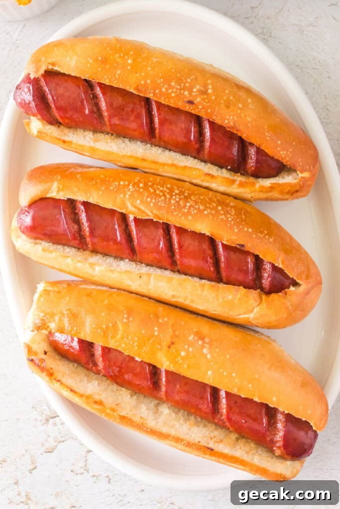 Crispy Air Fryer Hot Dogs: Quick, Juicy, and Ready in Minutes 2 Three fully cooked hot dogs in toasted hoagie buns on a white platter