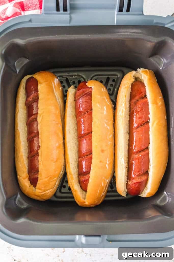 Crispy Air Fryer Hot Dogs: Quick, Juicy, and Ready in Minutes 8 Three hot dogs placed in buns inside the air fryer ready to be toasted