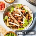 Plate with ground beef tacos and Instant Pot in the background.