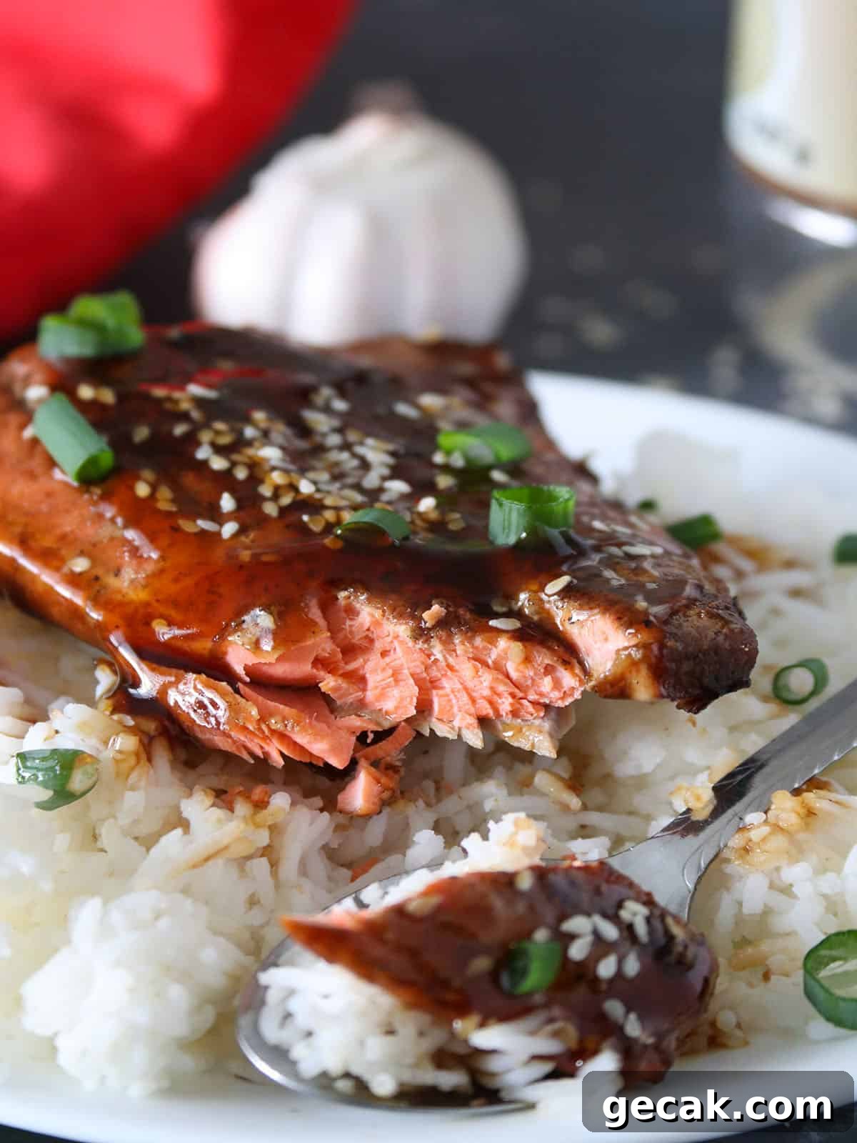 eating teriyaki Salmon over steamed rice on a black plate