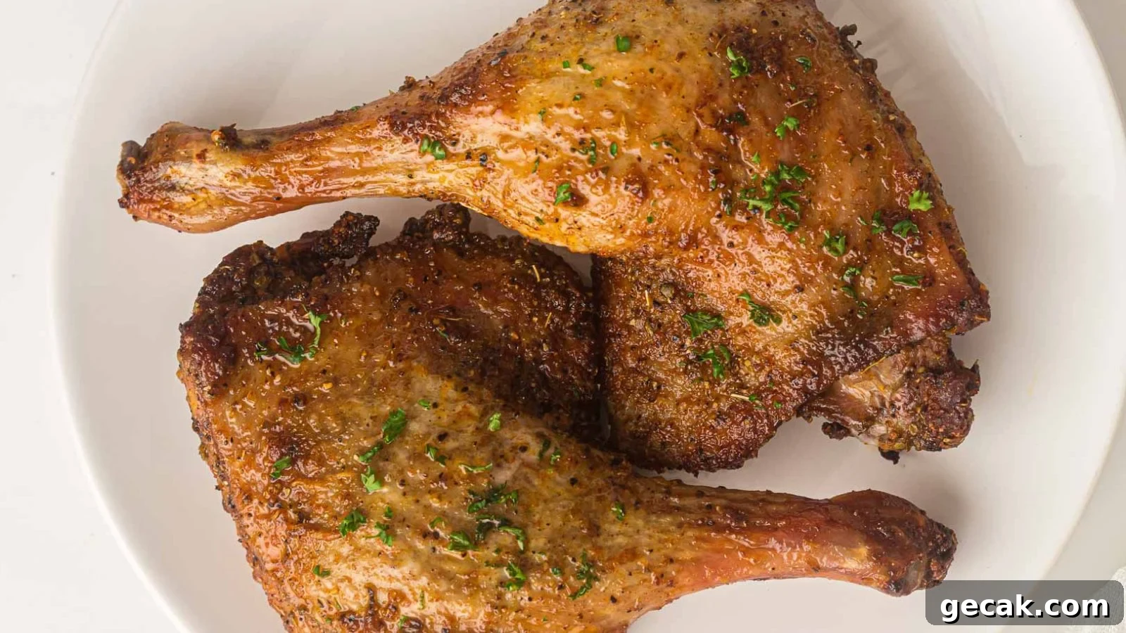 Crispy air fryer duck legs with rendered skin served with fresh herbs.