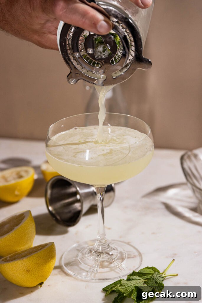 Straining the cocktail into the coupe cocktail glass. 