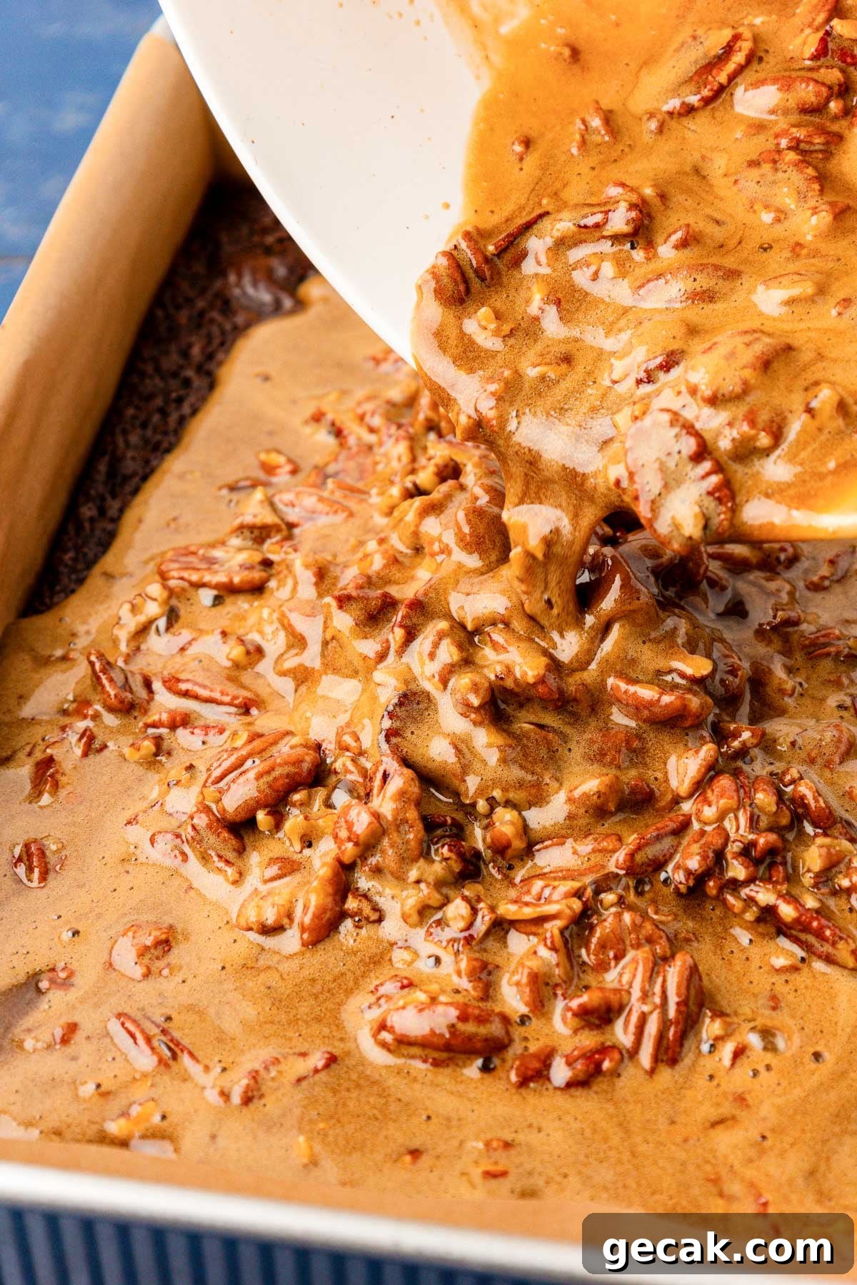 Pecan pie mixture being poured over brownies.