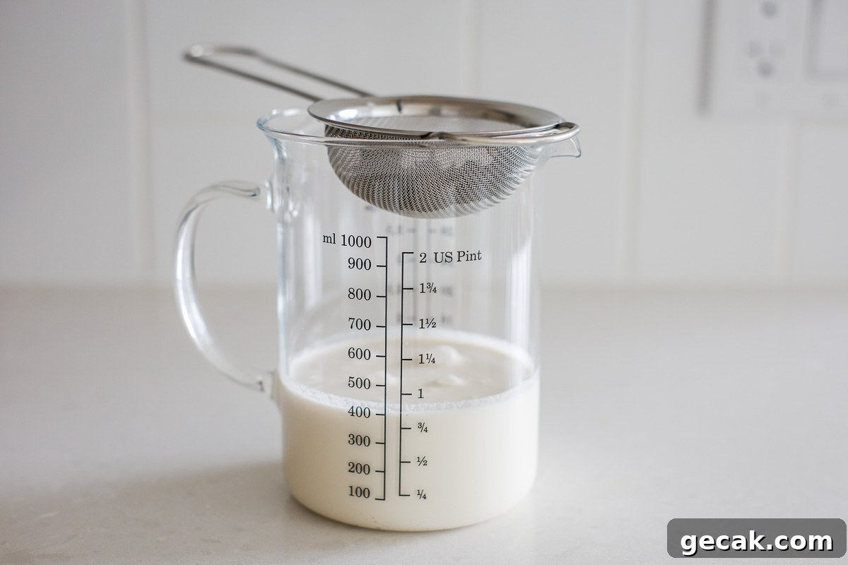 Cream mixture, fine mesh strainer, and a glass measuring container.
