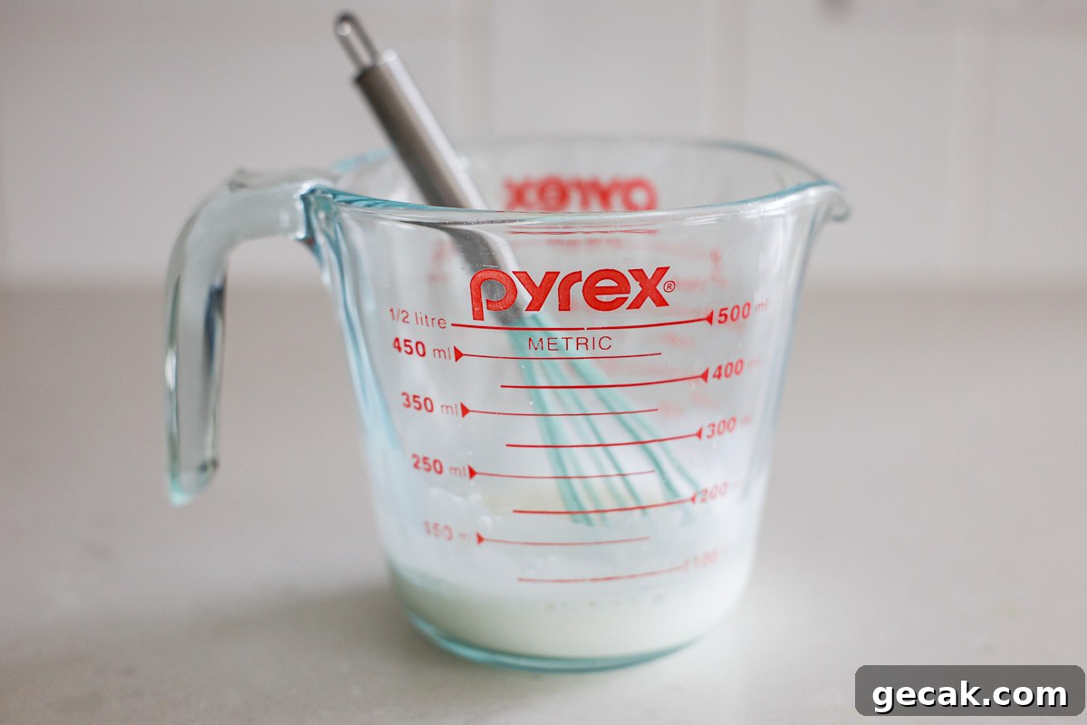 Cornstarch and water in a glass bowl with mini whisk.