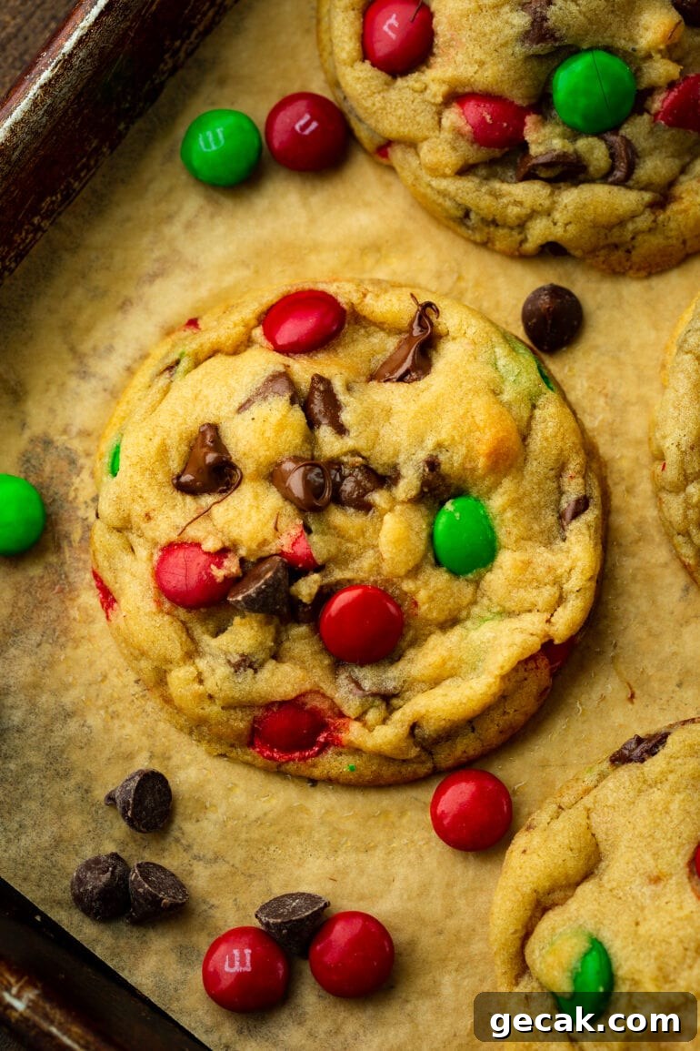 a photo taken over the top of a large golden baked thick and chewy chocolate chip cookie with Christmas m&m's in it.