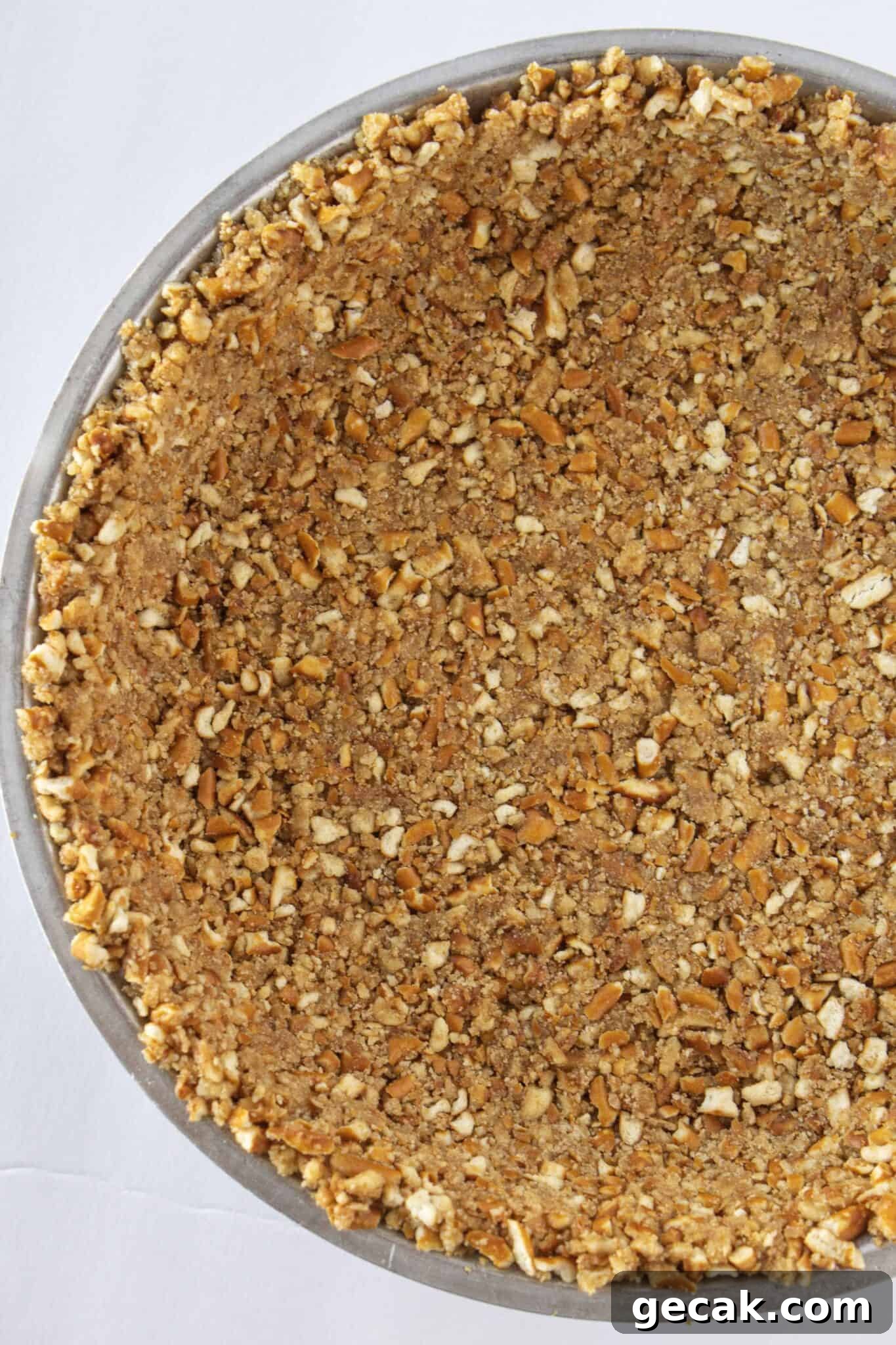 Pouring the pretzel mixture into a pie plate and pressing firmly into the pan.