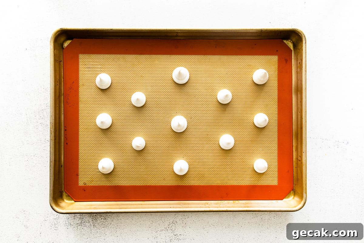 Dollops of meringue batter on a baking sheet.