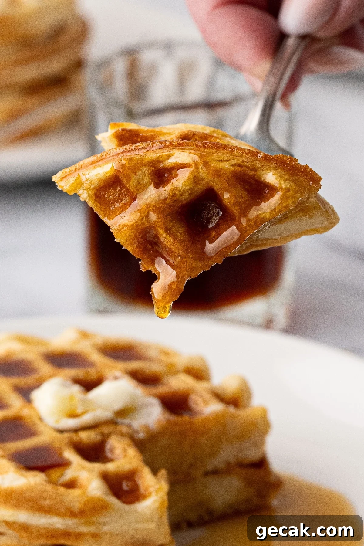Macro shot of the crispy texture and deep pockets of the homemade buttermilk waffle with melting butter and syrup.