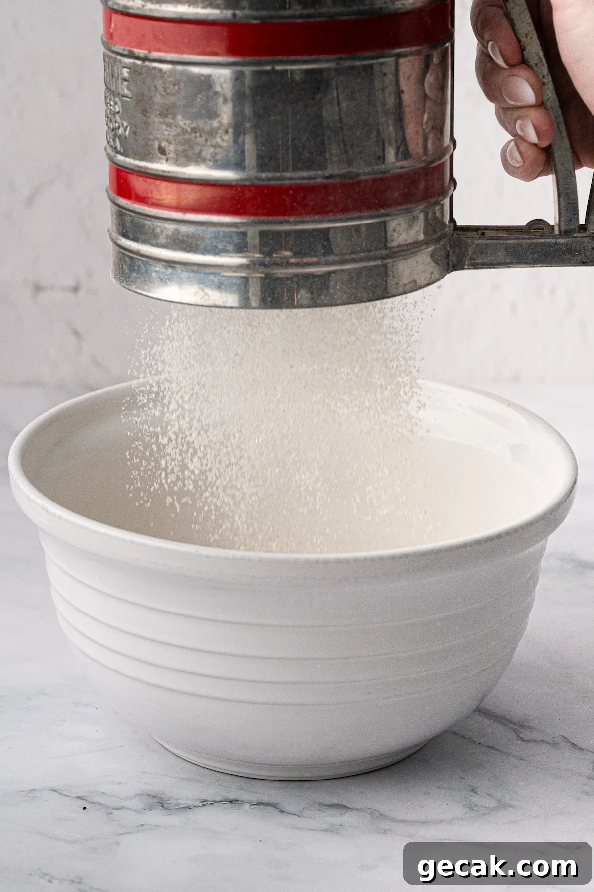 Sifting the dry ingredients together into a large ceramic mixing bowl for waffle batter.