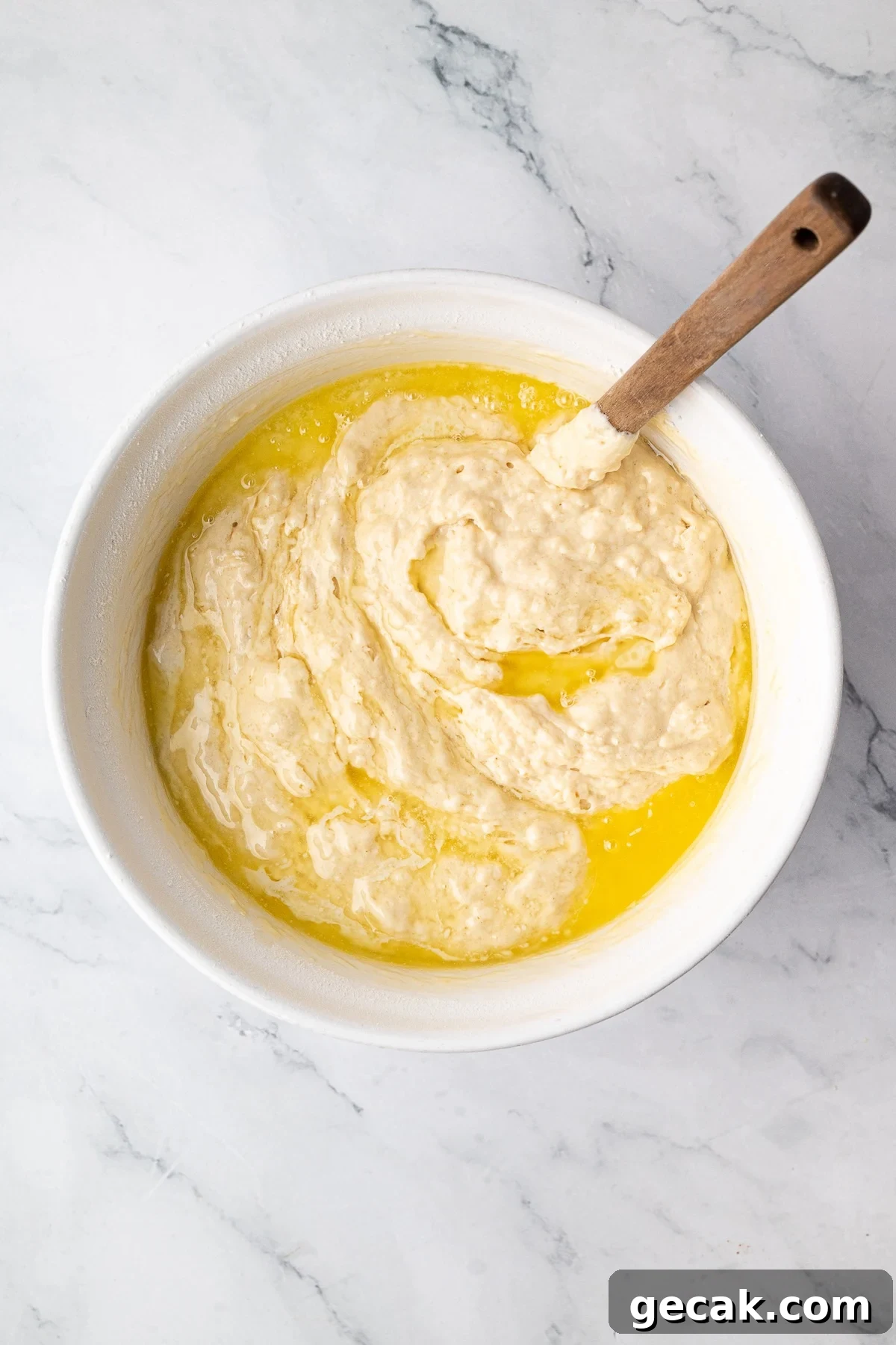 Slowly stirring melted butter and oil into thick buttermilk waffle batter until just incorporated.