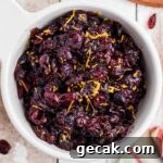 close up overhead image of a bowl of dried cranberry sauce with some orange zest sprinkled on top.