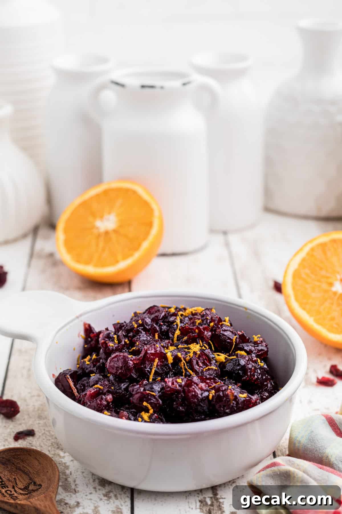 side on view of a bowl of dried cranberry sauce with some oranges in the background.