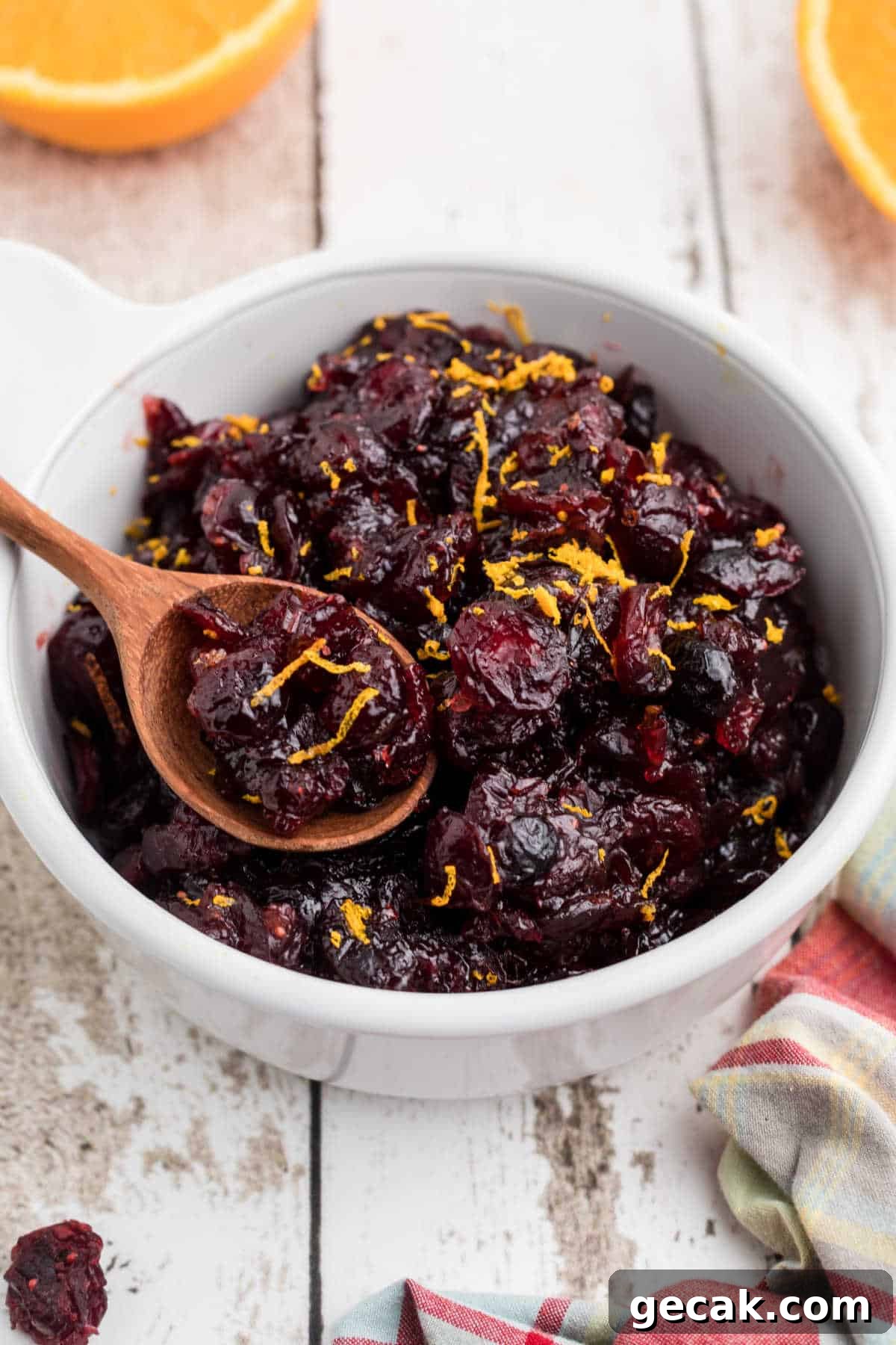 A close up of a bowl of dried cranberry sauce with a spoon digging in.