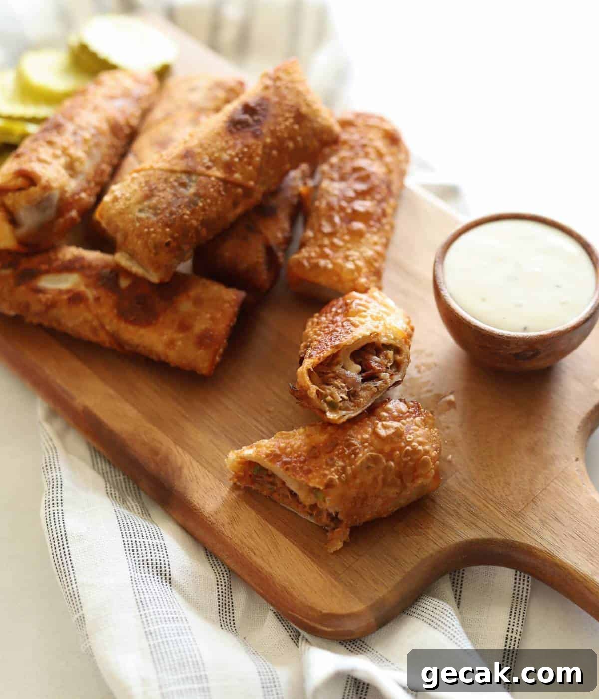 BBQ Pulled Pork Egg Rolls (Southern-Style Redneck Egg Rolls) 2 BBQ pulled pork egg rolls on wooden platter with side of ranch.