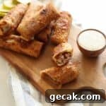 BBQ pulled pork egg rolls on wooden platter with side of ranch.