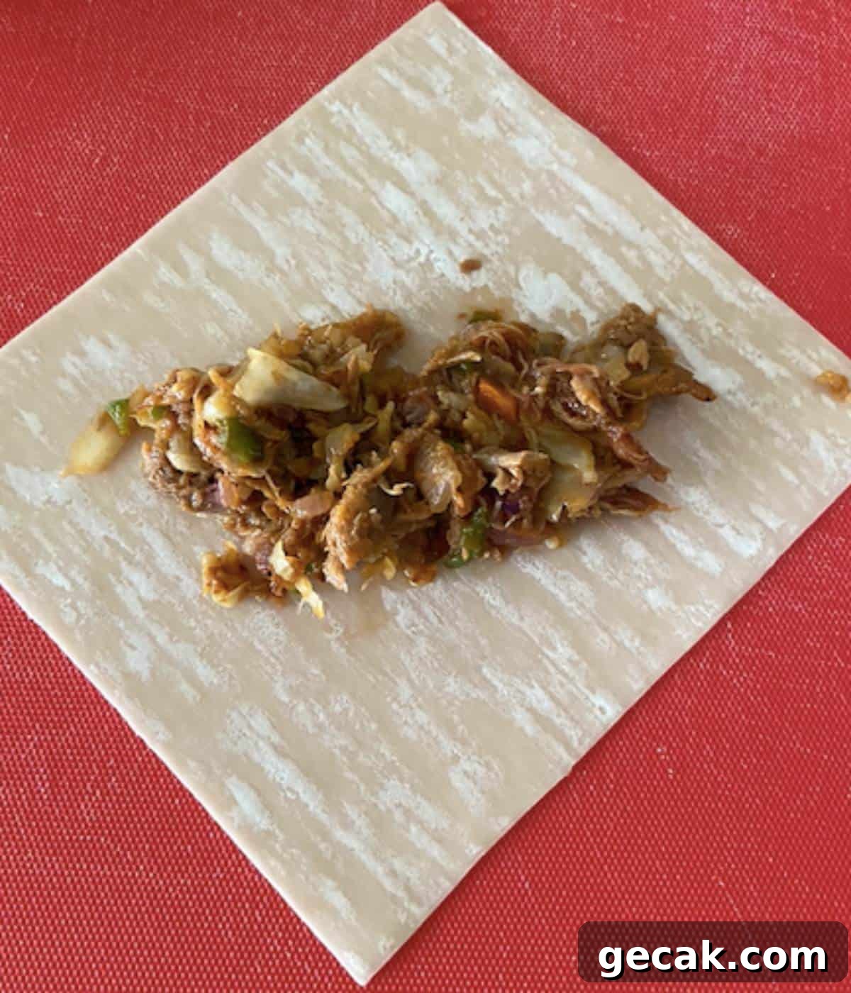 BBQ Pulled Pork Egg Rolls (Southern-Style Redneck Egg Rolls) 8 Pork filling on egg roll wrapper on cutting board.