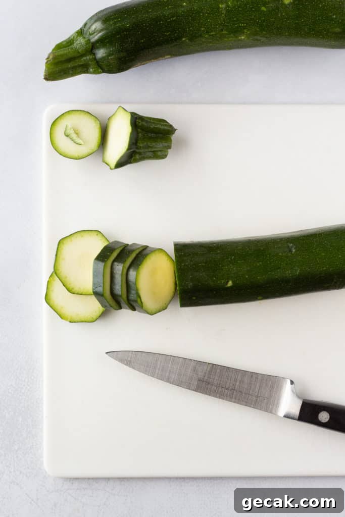 20-Minute Sautéed Zucchini and Mushrooms Recipe 6 zucchini being sliced on a white cutting board