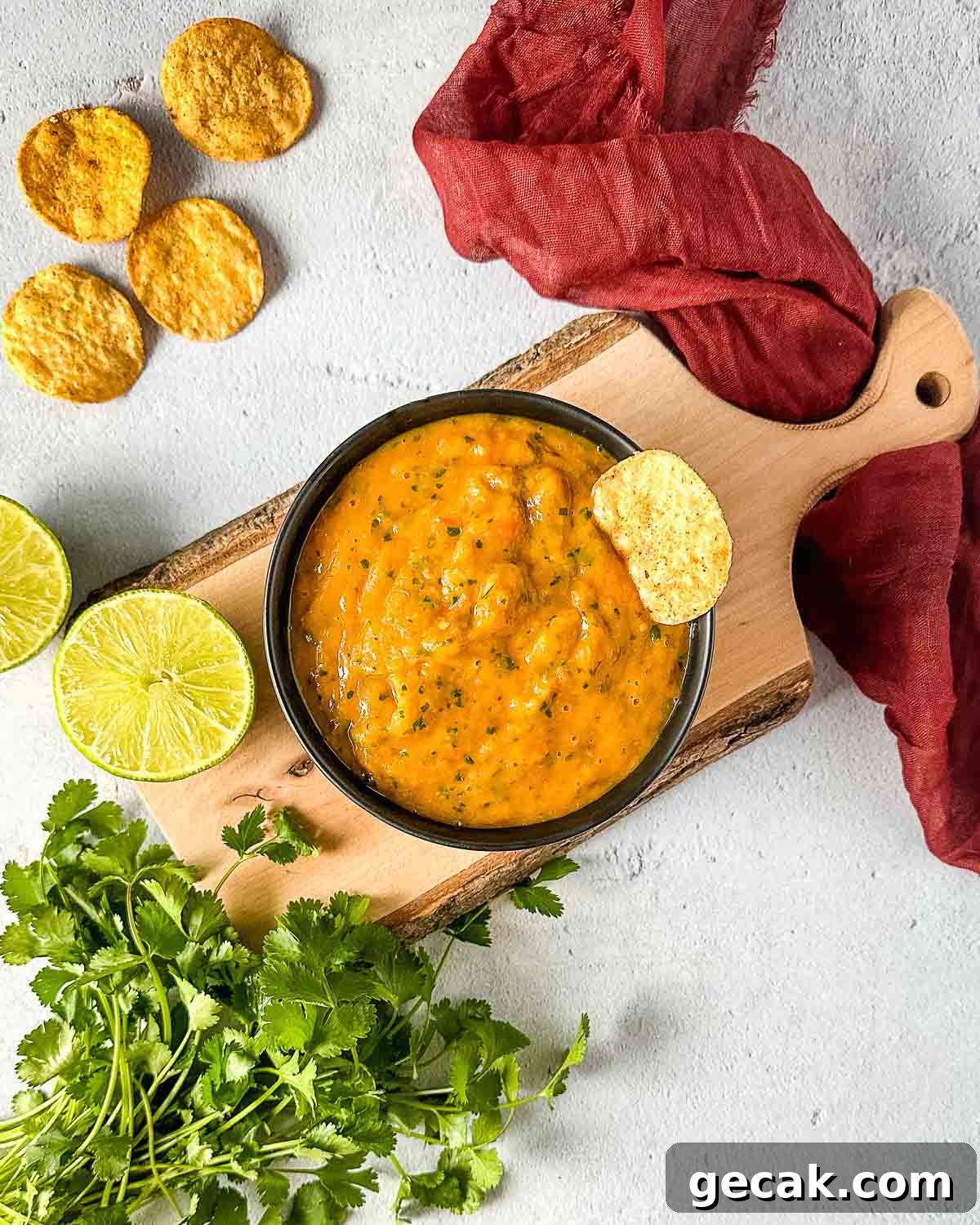 Roasted mango habanero salsa on a wooden cutting board surrounded by lime and cilantro.