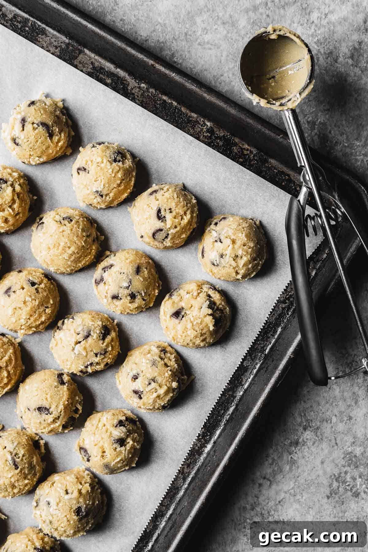 Scoops of cookie dough on a parchment lined baking pan.